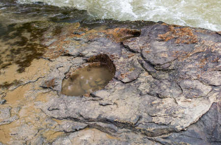 Hole in the rocky bank of a mountain river.の写真素材