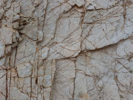 Texture of grey stone riddled with cracks.