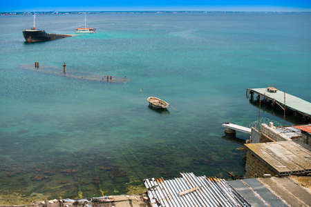 Sunken ship near old abandoned docks on the shore.の写真素材