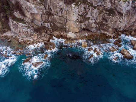 Airial view of the waves crashing on the rocks.