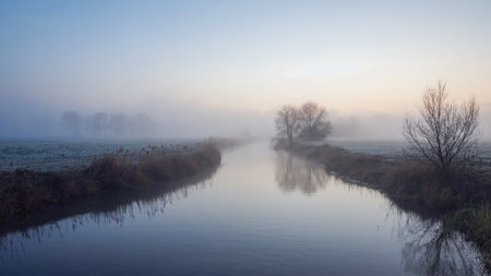 Panoramic view of a misty canal at sunrise in winterの素材
