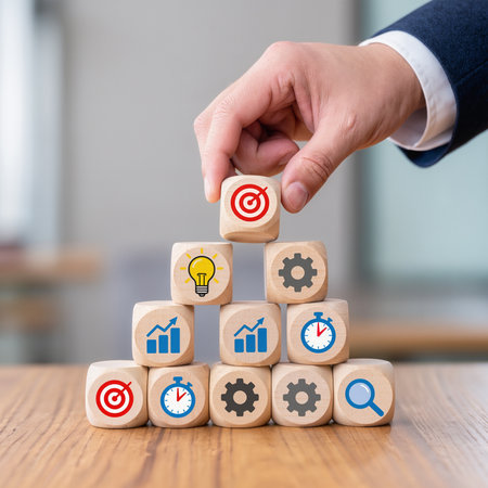 Businessman hand arranging wooden cube with target and gear icon on itの素材