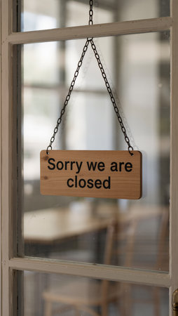 Wooden sign saying sorry we are closed hanging on the glass doorの素材