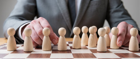 Businessman moving wooden figures on chess board, close-up viewの素材