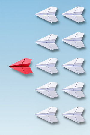 Leadership concept with red paper plane leading white paper planes on blue backgroundの素材