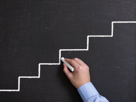 Hand drawing stairs on blackboard, closeup. Career growth conceptの素材