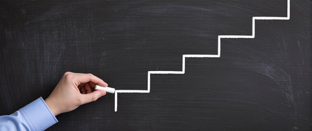 Hand drawing a staircase with chalk on blackboard, business success conceptの素材