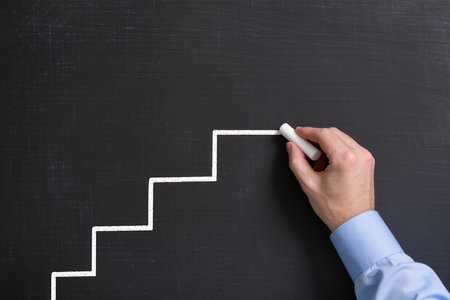 Businessman drawing stairs on blackboard, closeup. Success conceptの素材