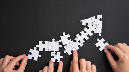 Hands connecting jigsaw puzzle pieces on black background, top viewの素材