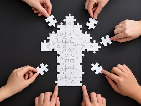 Hands connecting jigsaw puzzle pieces on black table, top viewの素材