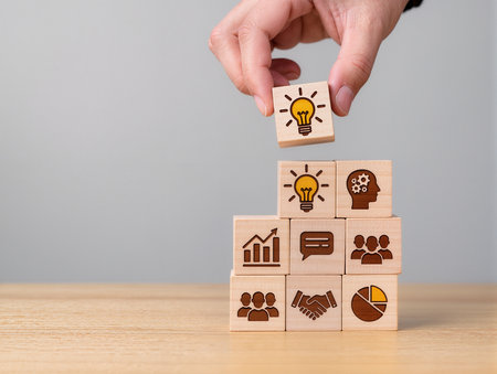 Businessman hand arranging wood block stacking as step stair with light bulb icon on top, business success conceptの素材
