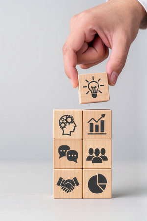 Businessman hand arranging wood cube with business icon on top, business success conceptの素材