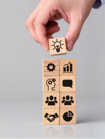 Conceptual image of human hand holding wooden cube with icons.の素材