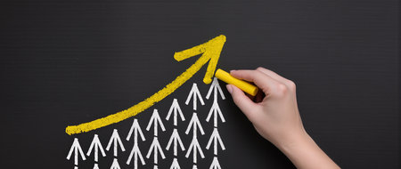 cropped view of woman drawing graph with yellow chalk on blackboardの素材