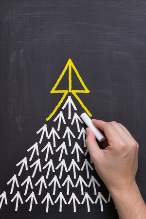 Leadership concept with a white chalk on a blackboard and an arrowの素材