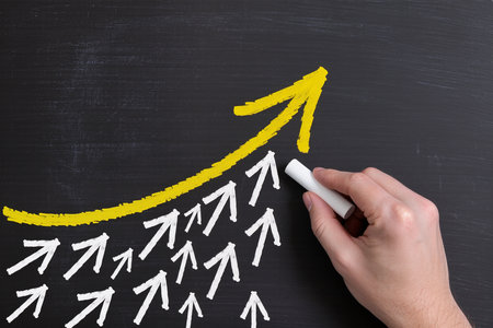 Hand drawing a chart with white chalk on blackboard, business conceptの素材