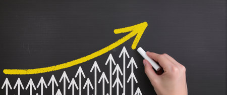 Hand drawing a graph on blackboard with a white chalk, business conceptの素材