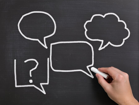 Hand drawing speech bubbles with chalk on blackboard, close-upの素材