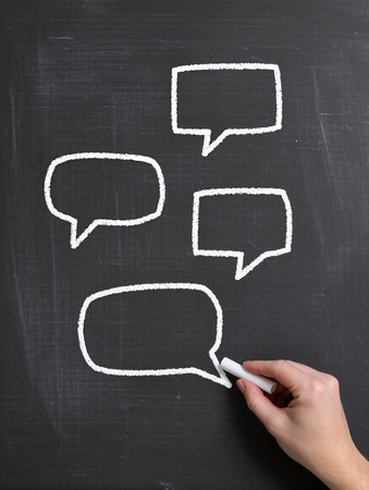 Speech bubbles drawn with white chalk on blackboard, closeupの素材