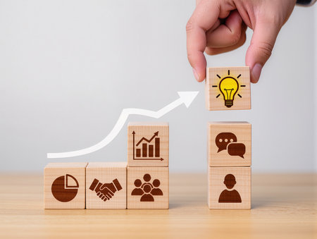 Businessman hand arranging wooden cube with light bulb icon on top, business idea conceptの素材