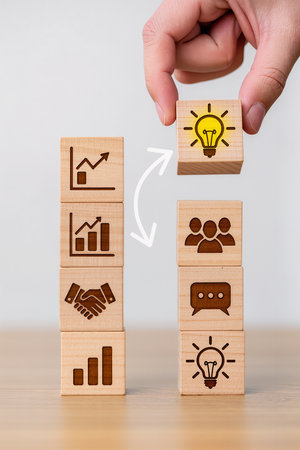 Businessman hand arranging wooden cube with light bulb icon on top, business idea conceptの素材
