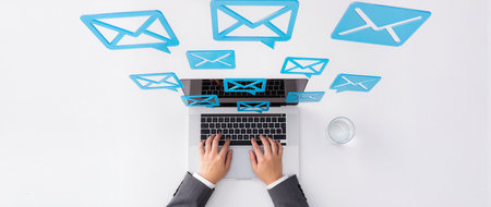 Top view of businesswoman sitting at desk and using laptop with email iconsの素材