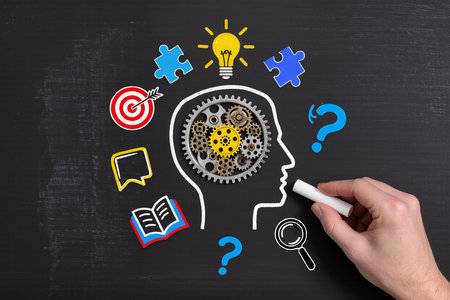 Idea concept on a blackboard with a hand drawing a human headの素材