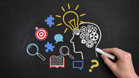 A person drawing a lightbulb with a chalk on a blackboardの素材