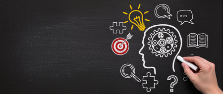 Brainstorming concept on a blackboard with a person drawing a gear wheelの素材