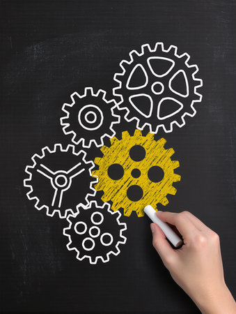 hand drawing gear wheels on blackboard, concept of teamwork and cooperationの素材