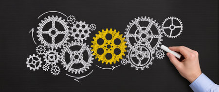 Businessman drawing gears with chalk on blackboard. Teamwork conceptの素材