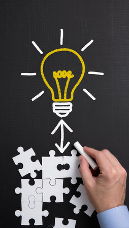 Hand drawing a light bulb on a blackboard with a white chalkの素材