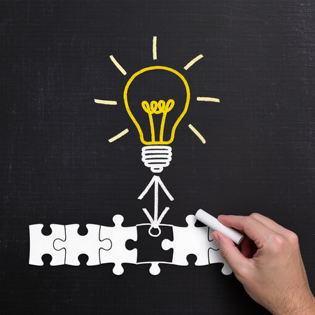 hand drawing a light bulb on a blackboard with a piece of puzzleの素材