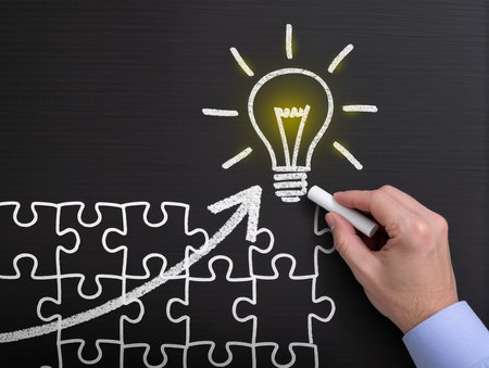 businessman drawing a light bulb on a blackboard with a chalkの素材