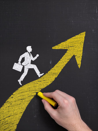 businessman drawing a chart on blackboard with yellow chalk, success conceptの素材