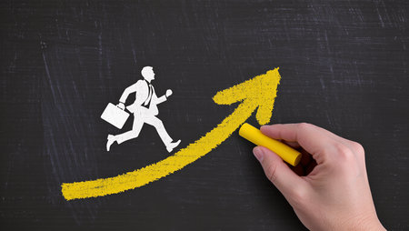 Businessman running up a chalkboard with a yellow arrow pointing upの素材