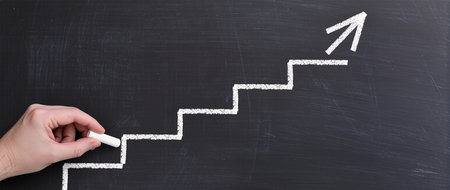 Hand drawing stairs with white chalk on blackboard, business success conceptの素材