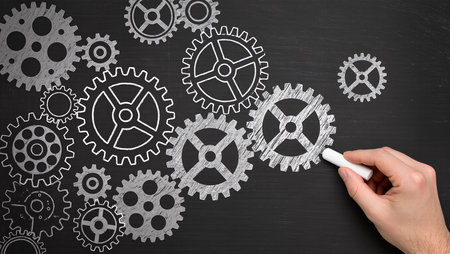 Hand drawing gear wheels on blackboard, concept of teamwork and cooperationの素材