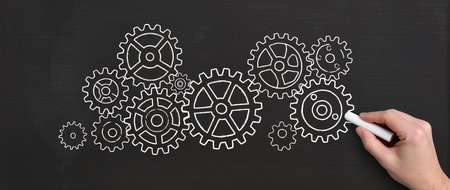 Hand drawing a gear mechanism on a blackboard with a white chalkの素材