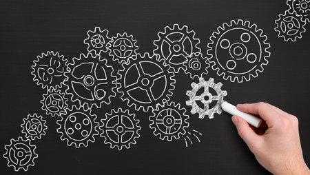 hand drawing gear wheels on blackboard, concept of teamwork and cooperationの素材