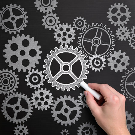 Hand drawing gear wheels on blackboard with white chalk. Teamwork conceptの素材