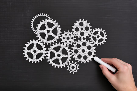 Hand drawing gears on blackboard, closeup. Teamwork conceptの素材