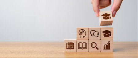 Concept of education with wooden cubes and icons on them over wooden tableの素材