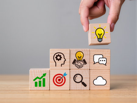 Hand holding wooden cube with business icon on wooden cubes. Success conceptの素材