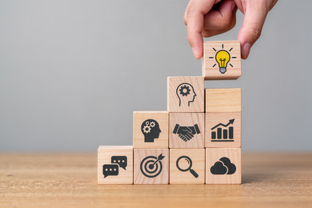 Businessman hand arranging wooden block stacking as step stair with business icons on table, business success and leadership conceptの素材