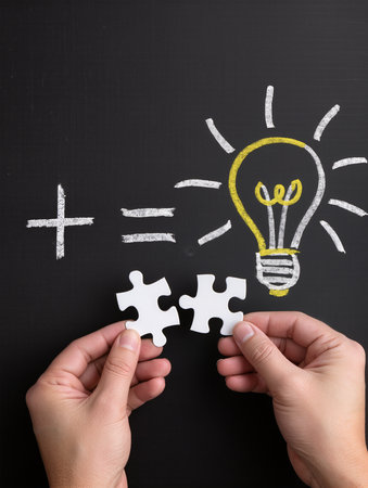Hands holding a puzzle piece with a lightbulb drawn on itの素材