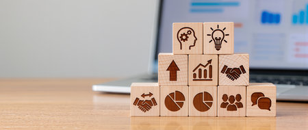 Wooden blocks with icons related to business and finance on a deskの素材