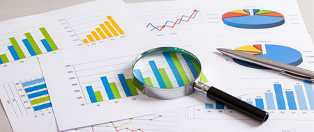 Magnifying glass on business charts and graphs. Financial analysis concept.の素材
