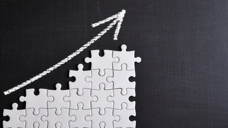 Pieces of jigsaw puzzle with rising arrow on blackboard backgroundの素材