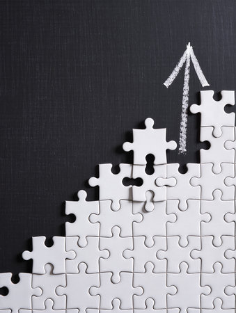 Top view of white jigsaw puzzle pieces with upward arrow on black backgroundの素材